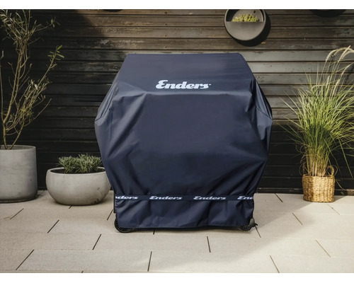 Enders Grill-Wetterschutzhülle auf einem Grill, platziert auf einer Terrasse mit Steinboden vor einer Holzwand und Topfpflanzen.