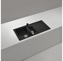 Einbau-Küchenspüle aus Granit-Verbundwerkstoff in Schwarz mit anderthalb Becken, Abtropffläche und passender schwarzer Armatur.