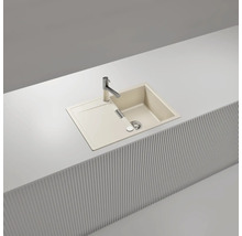 Beige Einbauspüle mit Abtropffläche und verchromter Armatur, eingelassen in eine weiße Arbeitsplatte mit Lamellenfront.