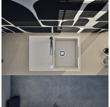 Moderne Küchenspüle mit Abtropffläche und Armatur in einer hellen Arbeitsplatte, kombiniert mit einer gemusterten Wand in einer hellen Küche.