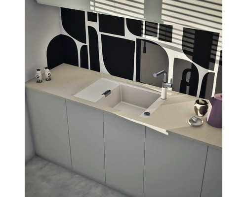 Moderne Einbauspüle mit Abtropffläche und Armatur in einer hellen Küche mit grafischem Fliesenspiegel.