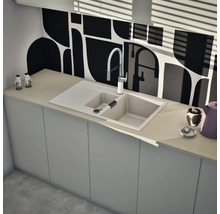 Moderne Küchenspüle mit zwei Becken, Abtropffläche und einer flexiblen Küchenarmatur auf einer hellen Arbeitsplatte vor einer gemusterten Rückwand.