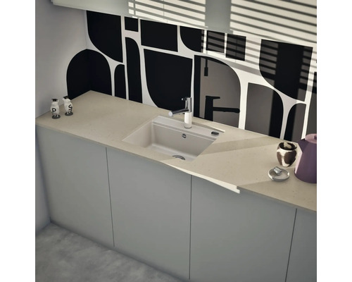Moderne Küche mit rechteckiger Einbauspüle, verchromter Armatur, heller Arbeitsplatte und gemusterter Rückwand.