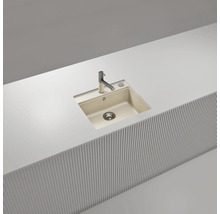 Moderne Einbauspüle mit einem Becken aus beigem Verbundwerkstoff, flächenbündig in einer weißen Arbeitsplatte mit verchromter Armatur.
