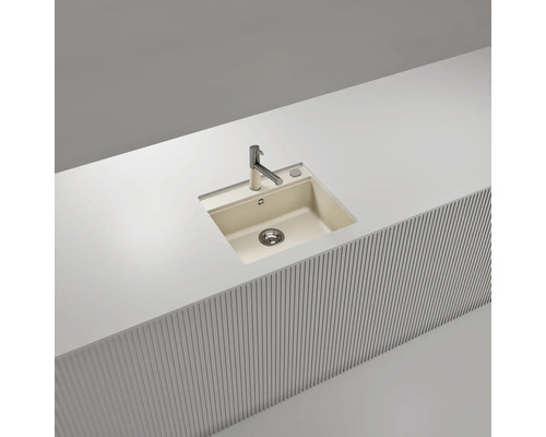Moderne Einbauspüle mit einem Becken aus beigem Verbundwerkstoff, flächenbündig in einer weißen Arbeitsplatte mit verchromter Armatur.