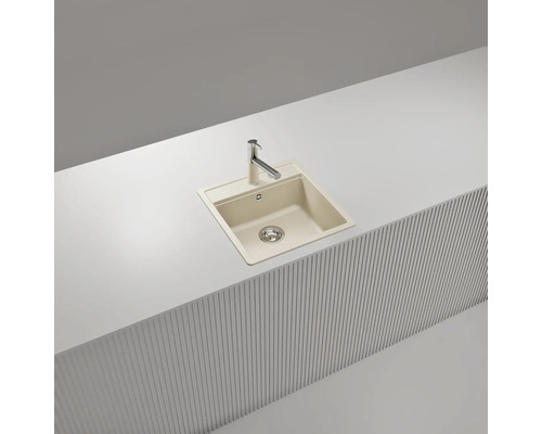 Beige Einbauspüle aus Quarzkomposit mit verchromter Küchenarmatur in einer weißen Arbeitsplatte.