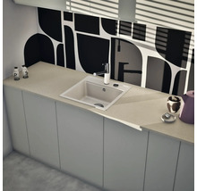 Moderne Küche mit quadratischer Einbauspüle, Armatur und heller Arbeitsplatte vor einer grafisch gemusterten Rückwand.