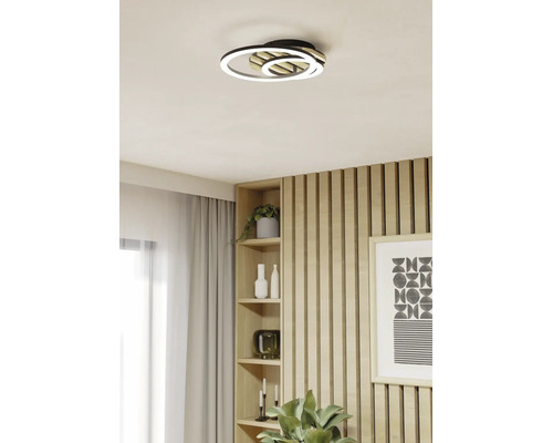 Moderne LED-Deckenleuchte mit zwei Ringen und Holzelementen in einem hellen Wohnraum mit Holzpaneelen.