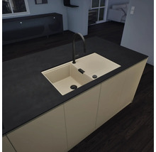 Moderne Kücheninsel mit beigefarbener Einbauspüle, schwarzer Armatur und schwarzer Arbeitsplatte in einer minimalistischen, aufgeräumten Küche.