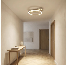 Moderne LED-Deckenleuchte in Ringform im Flur mit hellem Parkettboden in Fischgrätoptik und schmalem Konsolentisch aus Holz.