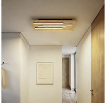 Moderne hölzerne Deckenleuchte mit horizontalen Lichtstäben in einem hellen, minimalistischen Flur mit Holztüren und Parkettboden.