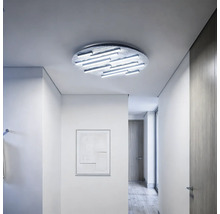 Moderne runde LED-Deckenleuchte mit linearen Lichtelementen in einem hellen, minimalistischen Flur mit Holzboden und strukturierten Oberflächen.