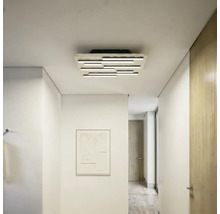 Moderne LED-Deckenleuchte mit mehreren versetzt angeordneten Lichtstäben in einem hellen, minimalistischen Flur mit weißen Wänden.