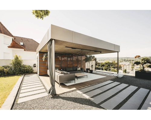 Moderne, helle Pergola aus Metall mit Holzlamellenwand, Vorhängen und Lounge-Möbeln auf einer Holzterrasse im Garten.