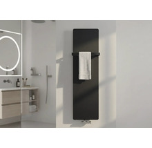 Moderner Heizkörper im Badezimmer, vertikaler Flachheizkörper in Schwarz mit Handtuchstange und weißem Handtuch in einem hellen Bad.