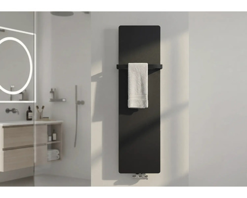 Moderner Heizkörper im Badezimmer, vertikaler Flachheizkörper in Schwarz mit Handtuchstange und weißem Handtuch in einem hellen Bad.