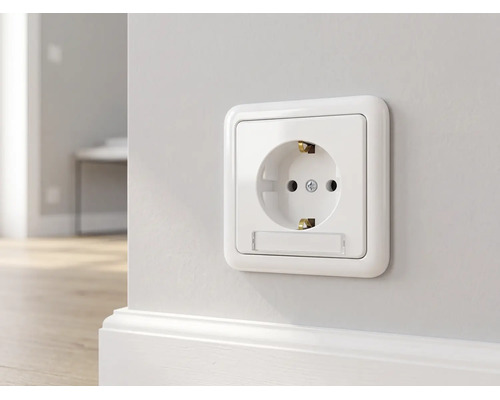 Schuko-Steckdose mit Beschriftungsfeld montiert an einer Wand über einer Fußleiste.