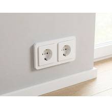 Doppelsteckdose Schuko montiert an einer Wand über einer weißen Fußleiste.