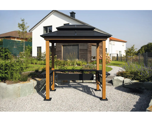 Grillpavillon mit dunklem Doppeldach, hellen Holzpfosten und integrierten Seitenablagen in einem modern gestalteten Garten vor einem Wohnhaus.