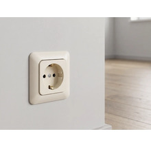 Schuko-Steckdose in Cremeweiß, montiert an einer hellen Wand in einem modernen Raum mit Holzboden.