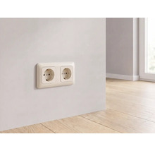 Doppelsteckdose montiert an einer hellen Wand über einem Holzboden in einem modernen, hellen Raum.