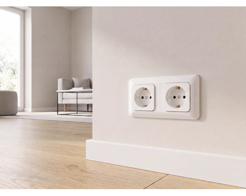 Weiße Zweifach-Schutzkontakt-Steckdose an einer Wand über einer Fußleiste in einem hellen, modern eingerichteten Wohnzimmer mit Holzboden.