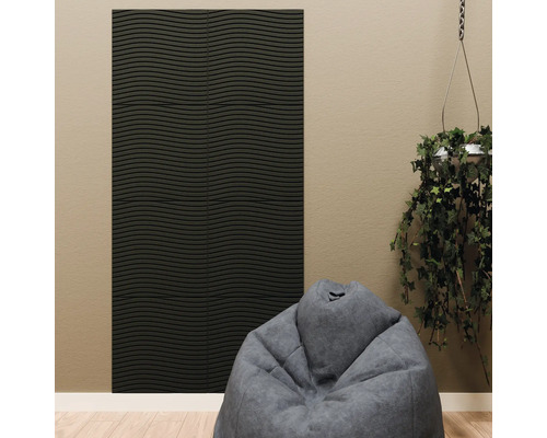 Schwarzes Akustikpaneel mit horizontaler Wellenstruktur an einer beigen Wand, kombiniert mit einem grauen Sitzsack und einer Hängepflanze.