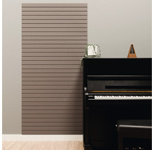 Akustikpaneel mit horizontalen Lamellen an einer Wand neben einem schwarzen Klavier in einem hellen Zimmer.