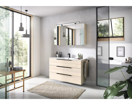 Modernes Badezimmer mit Waschtischunterschrank in heller Holzoptik, schwarzer Armatur, Spiegelschrank und großem Fenster für eine helle Atmosphäre.