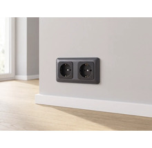 Horizontal montierte Doppelsteckdose mit Schutzkontakt an einer Wand über einer Fußleiste, moderner Stil, helle Raumatmosphäre.