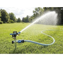 Impulsregner mit Erdspieß auf einem Rasen, angeschlossen an einen Gartenschlauch, sprüht einen weiten Wasserstrahl zur Gartenbewässerung.