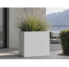 Großer quadratischer Pflanzkübel mit strukturierter Oberfläche und Ziergras auf einer modernen Terrasse.