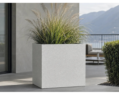 Großer quadratischer Pflanzkübel mit strukturierter Oberfläche und Ziergras auf einer modernen Terrasse.