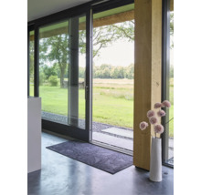 Rechteckige Schmutzfangmatte mit Blattmuster vor einer modernen Glasschiebetür mit Blick in den Garten und einer dekorativen Vase.