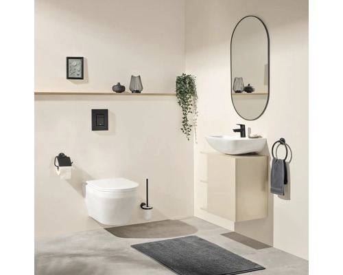 Modernes Badezimmer mit wandhängendem WC, weißem Aufsatzwaschbecken auf beigem Unterschrank, schwarzer Armatur, ovalem Spiegel und grauer Matte.