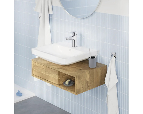 Modernes Badezimmer mit Aufsatzwaschbecken auf einem wandhängenden Waschtischunterschrank in Holzoptik vor einer gefliesten Wand.