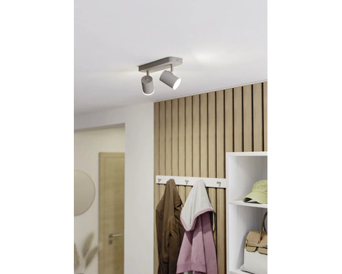 Moderner zweiflammiger Deckenstrahler in einem hellen Flur mit Wandpaneelen aus Holzlamellen und einer Garderobe.
