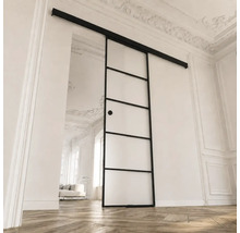Schiebetür aus Glas mit schwarzem Metallrahmen und Sprossen in einem hellen Raum mit Stuckdecke und Parkettboden.