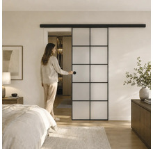 Moderne Schiebetür mit schwarzem Metallrahmen und Milchglas-Elementen in einem hellen Schlafzimmer mit begehbarem Kleiderschrank.