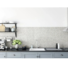 Küchenrückwand in Terrazzo-Optik in einer modern gestalteten Küche mit dunkler Arbeitsplatte, weißer Spüle und hellgrauen Schränken.