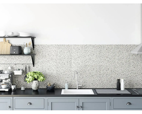 Küchenrückwand in Terrazzo-Optik in einer modern gestalteten Küche mit dunkler Arbeitsplatte, weißer Spüle und hellgrauen Schränken.