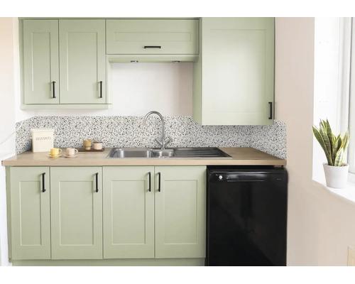 Moderne Küche mit salbeigrünen Schränken, schwarzen Griffen, Küchenrückwand in Terrazzo-Optik, Edelstahlspüle und Arbeitsplatte in Holzoptik.