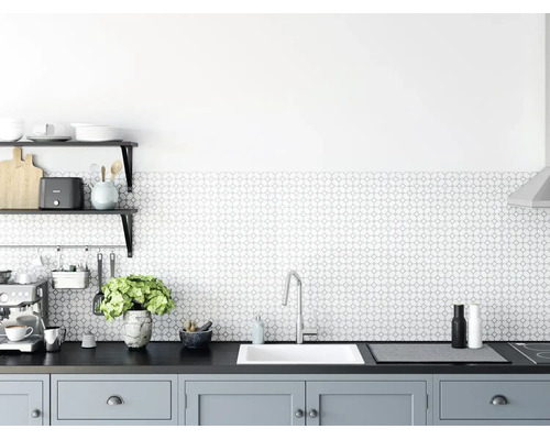Moderne, helle Küche mit geometrisch gemustertem Fliesenspiegel, weißer Einbauspüle, Armatur aus Chrom und grauen Unterschränken.