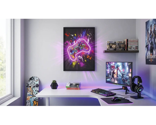 Heller Gaming-Raum mit Schreibtisch, Gaming-Monitor und Zubehör. Ein gerahmtes Wandbild mit Controller-Motiv dekoriert den Raum.