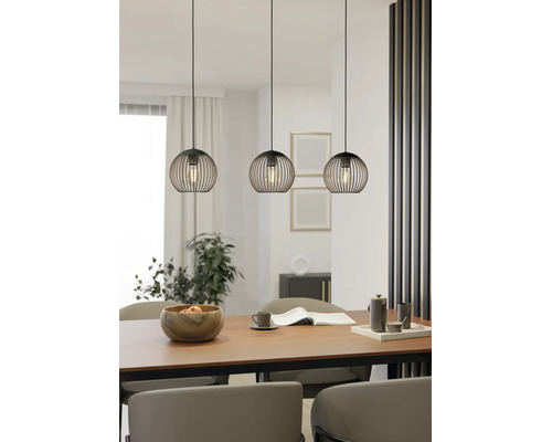 Drei schwarze Pendelleuchten im Käfig-Design über einem Holztisch in einem hellen, modern eingerichteten Esszimmer mit Pflanzen.
