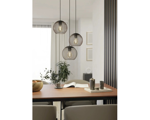 Dreiflammige Pendelleuchte mit schwarzen Drahtschirmen in Kugelform über einem Esstisch aus Holz in einem modern gestalteten Esszimmer.