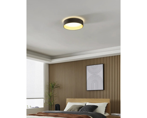 Helles, modernes Schlafzimmer mit einer runden Deckenleuchte, Wandpaneelen aus Holzlatten, einem Bett und einem Fenster mit Jalousien.