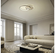 Moderne LED-Deckenleuchte mit ineinandergreifenden Ringen in einem hellen, elegant eingerichteten Wohnzimmer mit Sofa und Couchtisch.