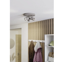 Grauer dreiflammiger Deckenstrahler an einer weißen Decke in einem modernen Flur mit Holzlamellenwand und Garderobe.