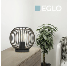 Moderne Eglo Tischleuchte aus Metall im Gitterdesign auf einer Holzkommode neben einer Zimmerpflanze in einem hellen Raum. Eglo Logo.